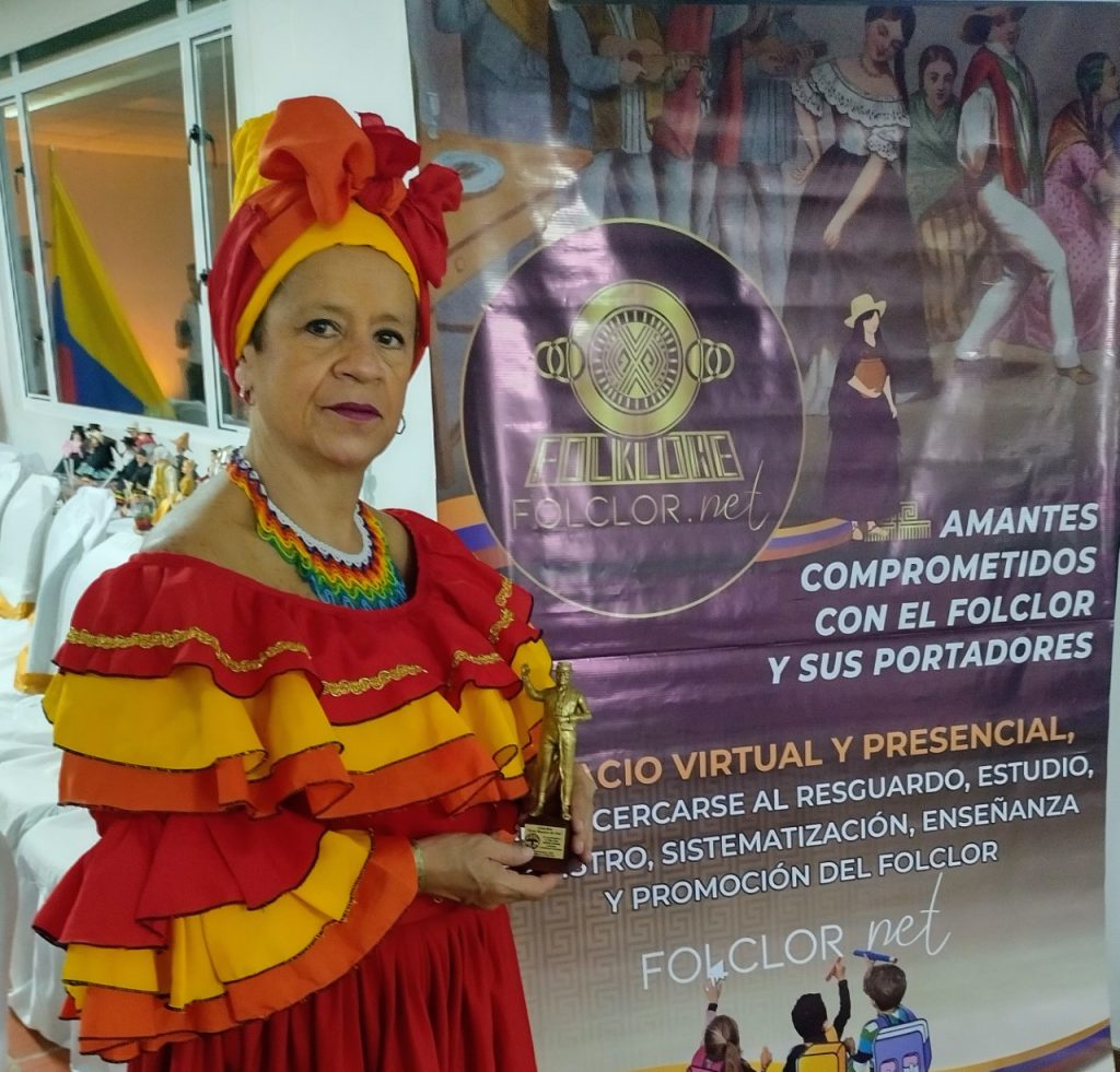 Fotografía de la maestra Maria Elisa Alfaro con su premio Gran maestro de Oro